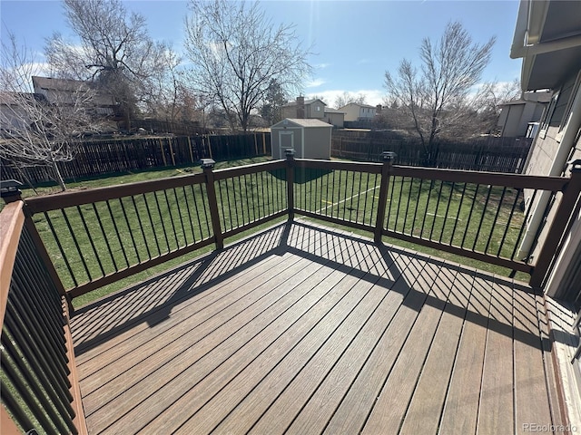 wooden deck featuring a yard, a fenced backyard, an outdoor structure, and a shed