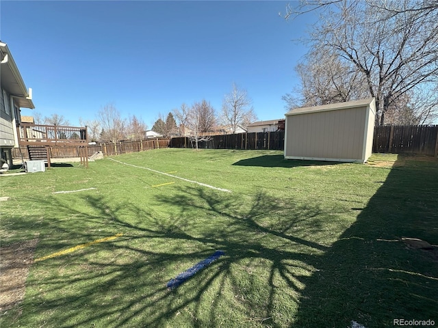 view of yard with a deck, an outbuilding, a fenced backyard, and a shed