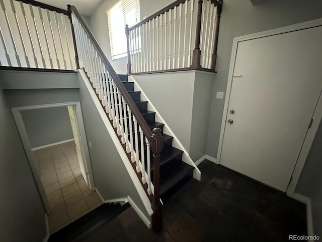 stairway featuring a high ceiling and baseboards