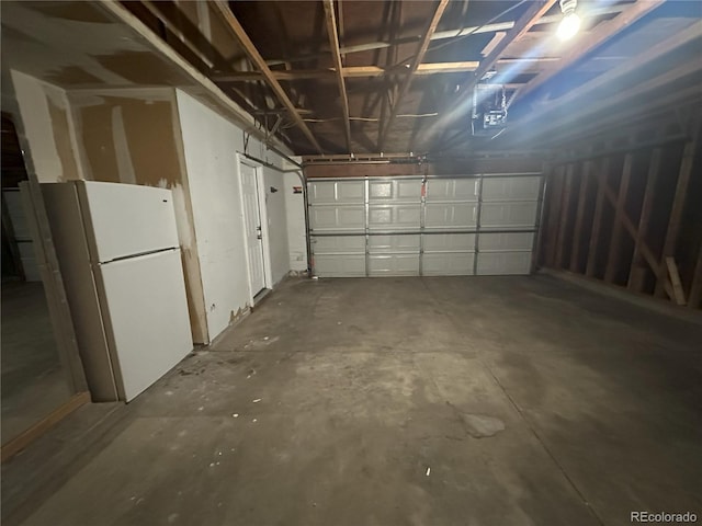 garage with a garage door opener and freestanding refrigerator