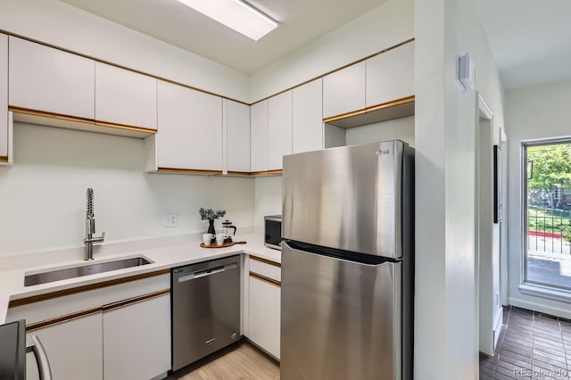 2120 W 31st Ave, Denver, CO 80211 - kitchen featuring light wood finished floors, a sink, white cabinetry, light countertops, and appliances with stainless steel finishes