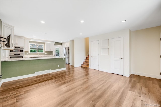 16135 E Baker Pl, Aurora, CO 80013 - unfurnished living room with stairs, light wood finished floors, and recessed lighting