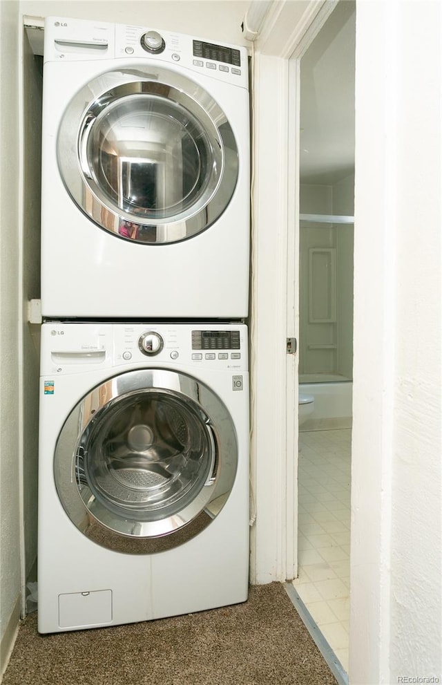 clothes washing area featuring stacked washer and dryer and tile patterned flooring