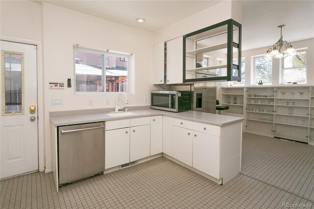 kitchen with appliances with stainless steel finishes, sink, decorative light fixtures, an inviting chandelier, and white cabinets