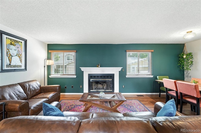 8468 S Upham Way, Littleton, CO 80128 - living area with a textured ceiling, plenty of natural light, wood finished floors, and a glass covered fireplace