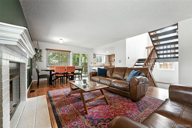 8468 S Upham Way, Littleton, CO 80128 - living room with light wood-style floors, a textured ceiling, stairway, and a brick fireplace