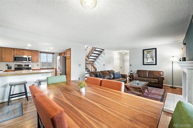 8468 S Upham Way, Littleton, CO 80128 - dining space featuring stairs, light wood-style flooring, a textured ceiling, and recessed lighting