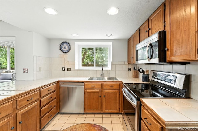 8468 S Upham Way, Littleton, CO 80128 - kitchen featuring stainless steel appliances, tile countertops, brown cabinets, and recessed lighting