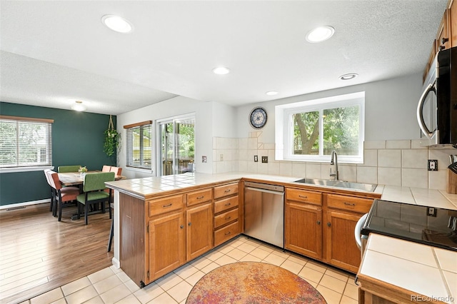 8468 S Upham Way, Littleton, CO 80128 - kitchen with appliances with stainless steel finishes, a peninsula, tile countertops, plenty of natural light, and recessed lighting