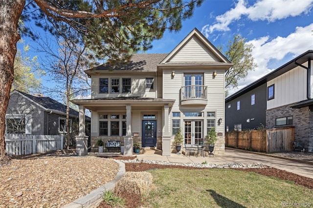view of front facade with fence, a shingled roof, a balcony, french doors, and covered porch