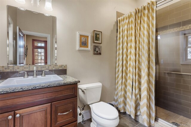 bathroom with vanity, tile patterned floors, toilet, and tiled shower