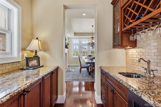 bar with indoor bar, decorative backsplash, a sink, and dark wood-type flooring