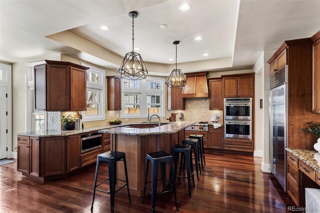 kitchen with dark wood-style floors, a kitchen bar, a center island, custom range hood, and stainless steel appliances