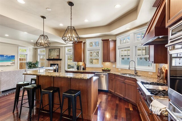 kitchen featuring open floor plan, tasteful backsplash, a sink, dark wood finished floors, and appliances with stainless steel finishes
