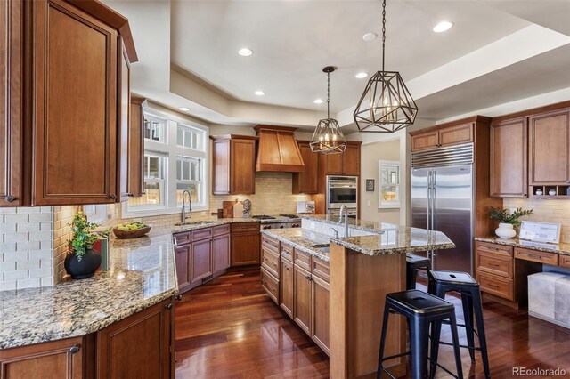 kitchen featuring decorative backsplash, appliances with stainless steel finishes, a sink, dark wood-style floors, and custom range hood