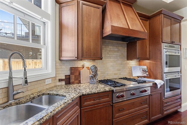 kitchen with a sink, stainless steel appliances, tasteful backsplash, and custom exhaust hood