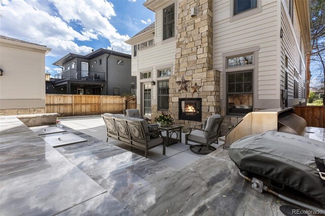 view of patio / terrace with an outdoor living space with a fireplace, fence, and area for grilling