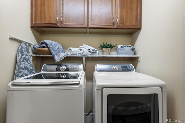 clothes washing area with washing machine and clothes dryer and cabinet space