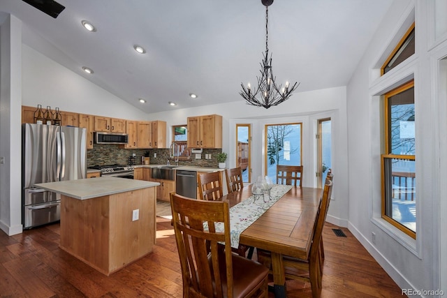 kitchen featuring visible vents, dark wood-style floors, vaulted ceiling, stainless steel appliances, and backsplash