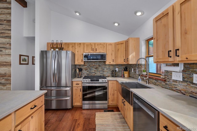 kitchen with lofted ceiling, appliances with stainless steel finishes, light countertops, and a sink