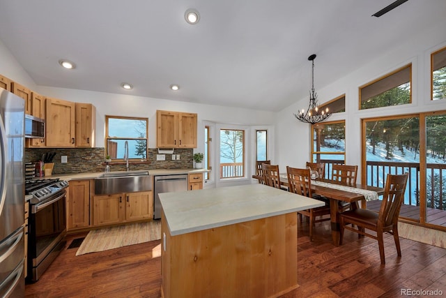 kitchen featuring stainless steel appliances, a sink, vaulted ceiling, backsplash, and dark wood-style floors