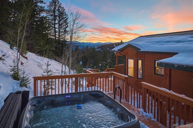 snow covered deck featuring a mountain view and a hot tub