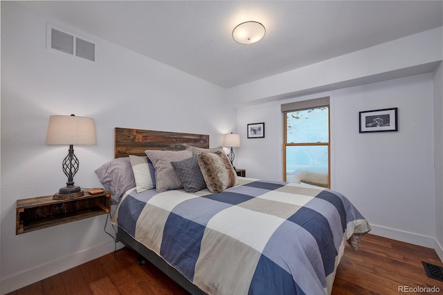 bedroom featuring visible vents, baseboards, and wood finished floors