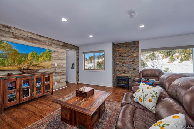 living room with baseboards, wood finished floors, a wood stove, and recessed lighting