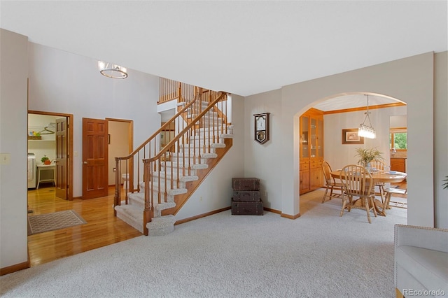 3 Silverberry, Littleton, CO 80127 - living room featuring carpet, arched walkways, stairway, a chandelier, and separate washer and dryer
