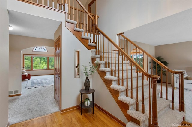 3 Silverberry, Littleton, CO 80127 - staircase featuring wood finished floors, arched walkways, a high ceiling, and carpet flooring