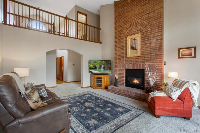 3 Silverberry, Littleton, CO 80127 - carpeted living room featuring a towering ceiling, arched walkways, and a fireplace