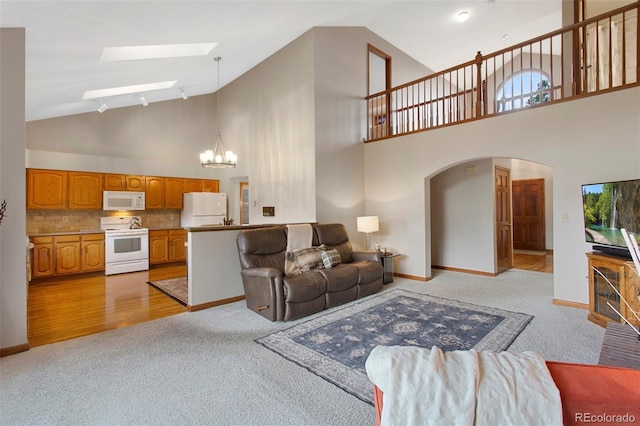 3 Silverberry, Littleton, CO 80127 - living room featuring light carpet, a skylight, a chandelier, arched walkways, and high vaulted ceiling