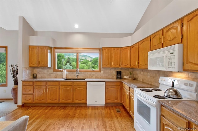 3 Silverberry, Littleton, CO 80127 - kitchen with white appliances, lofted ceiling, tasteful backsplash, brown cabinets, and light wood-style floors