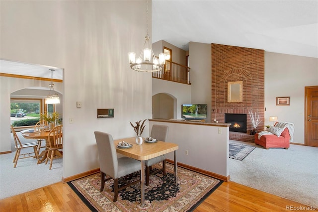 3 Silverberry, Littleton, CO 80127 - dining room with a chandelier, high vaulted ceiling, a brick fireplace, wood finished floors, and carpet flooring