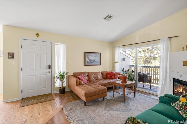 8405 Pebble Creek Way Unit 202, Highlands Ranch, CO 80126 - living area featuring wood finished floors, a glass covered fireplace, and vaulted ceiling