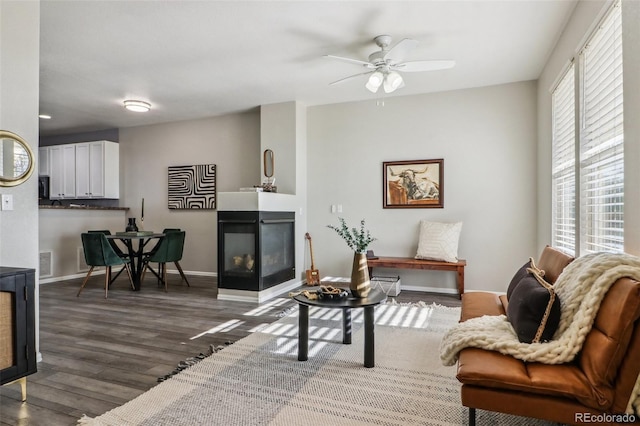 15612 E 96th Way Unit 13E, Commerce City, CO 80022 - living area with a multi sided fireplace, wood finished floors, a ceiling fan, and baseboards