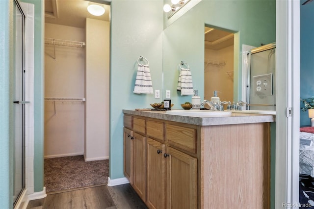 15612 E 96th Way Unit 13E, Commerce City, CO 80022 - ensuite bathroom featuring wood finished floors, a shower with door, a spacious closet, vanity, and baseboards