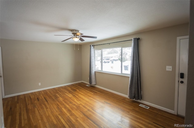 empty room featuring a textured ceiling, hardwood / wood-style flooring, and ceiling fan