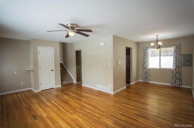 spare room featuring electric panel, hardwood / wood-style flooring, and ceiling fan with notable chandelier