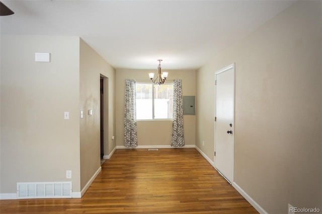 unfurnished dining area featuring hardwood / wood-style floors, a chandelier, and electric panel