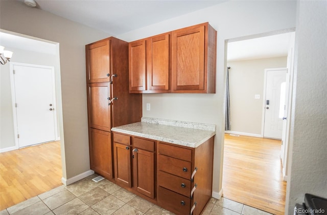 kitchen with light hardwood / wood-style floors, a chandelier, and light stone counters