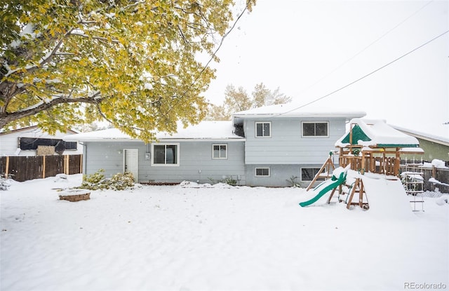 snow covered rear of property with a playground