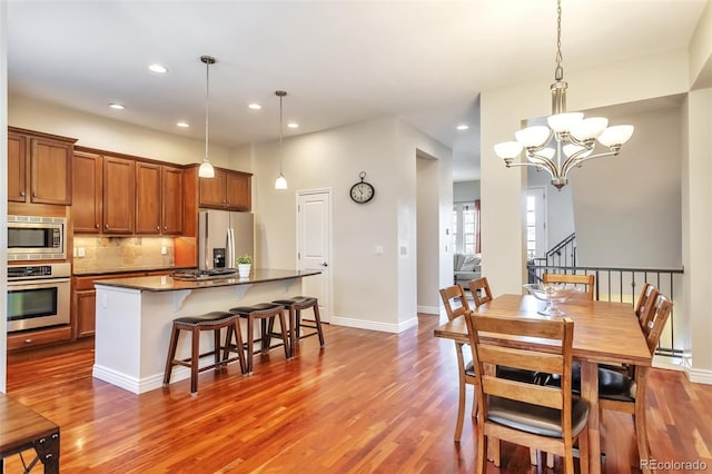 dining room with wood finished floors, a chandelier, recessed lighting, baseboards, and baseboard heating