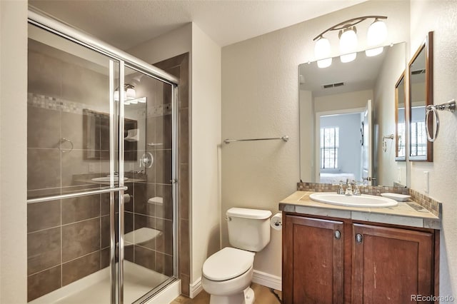 full bathroom featuring a textured wall, toilet, a shower stall, and vanity