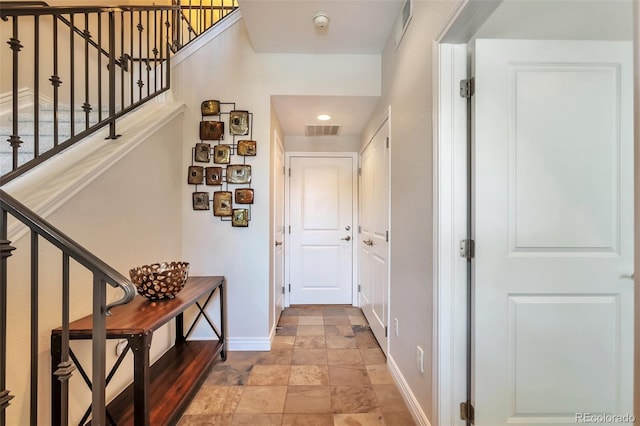 hall with baseboards, stone finish floors, and stairs