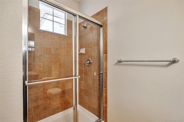 bathroom with tiled shower and a textured wall