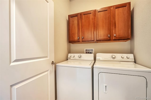 clothes washing area featuring cabinet space and washer and clothes dryer