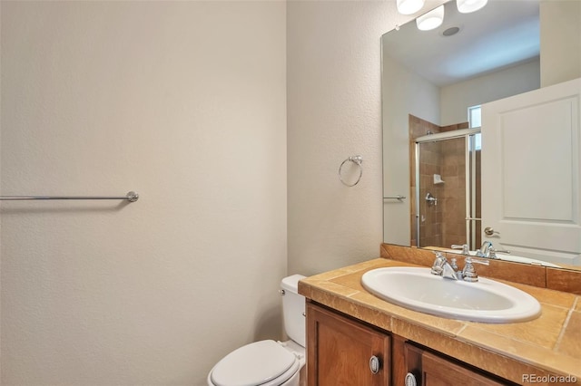 full bath featuring a stall shower, vanity, a textured wall, and toilet