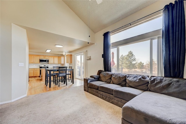 living room featuring light carpet, high vaulted ceiling, baseboards, and a textured ceiling