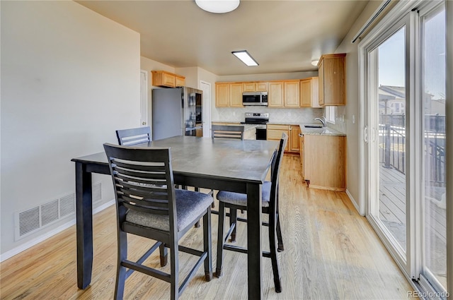 dining room featuring light wood-type flooring, visible vents, and baseboards